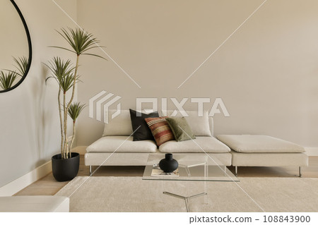 a living room with a couch, coffee table and two planters on the floor in front of the sofa 108843900