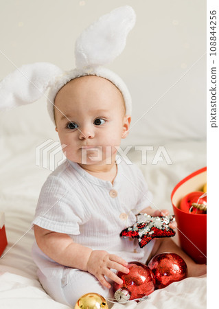 Christmas Baby in Santa Hat Child playing with baubles. Present Gift Box over Holiday Lights background and Merry Christmas concept. Generation alpha and gen alpha Christmas Baby in Santa Hat Child playing with baubles. Present Gift Box over Holiday Lights background and Merry Christmas concept. Generation alpha and gen alpha 108844256