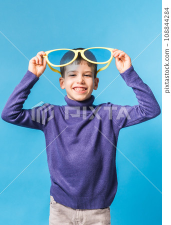 Cheerful little boy in big glasses express a surprised face isolated on blue background. Generation alpha and gen alpha children. 108844284