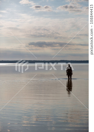 Silhouette of a woman going to swim in the lake Silhouette of a woman going to swim in the lake 108844415