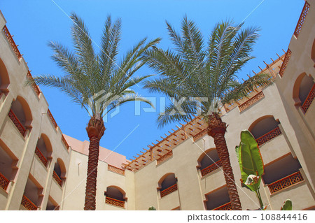 View of building of resort with palm trees. Egyptian resort. Tropical holidays View of building of resort with palm trees. Egyptian resort. Tropical holidays 108844416