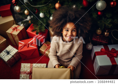 Happy little african american smiling girl with christmas gift boxes on floor Happy little african american smiling girl with christmas gift boxes on floor 108844481