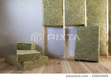 Wooden frame for future walls with drywall plates insulated with rock wool and fiberglass insulation staff for cold barrier. Comfortable warm home, economy, construction and renovation concept. Wooden frame for future walls with drywall plates insulated with rock wool and fiberglass insulation staff for cold barrier. Comfortable warm home, economy, construction and renovation concept. 108844904