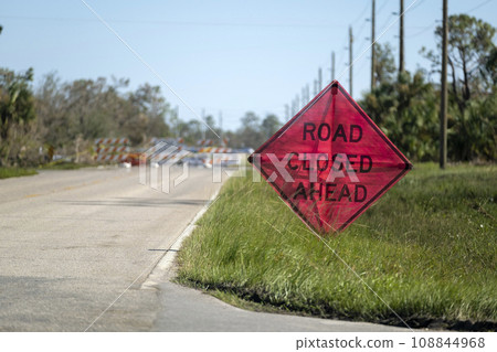 Warning roadworks sign and safety barrier on city street during maintenance repair work 108844968
