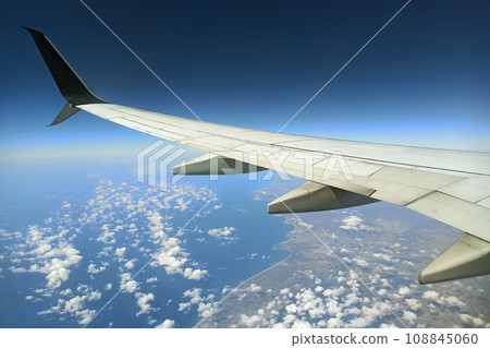 View through airplane window of commercial jet plane wing flying high in the sky. Air travelling concept 108845060