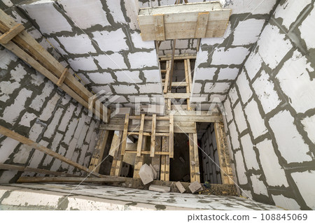 View from above of future multi stored cottage energy saving walls of large white hollow foam insulation blocks and temporary wooden scaffolding frame. Construction masonry, modern technology concept. 108845069