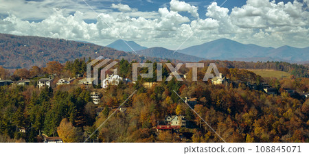 View from above of expensive residential houses high on hill top between yellow fall trees in suburban area in North Carolina. American dream homes as example of real estate development in US suburbs View from above of expensive residential houses high on hill top between yellow fall trees in suburban area in North Carolina. American dream homes as example of real estate development in US suburbs 108845071