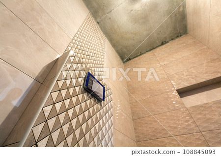 Unfinished reconstruction of bathroom or toilet with light beige geometric mosaic ceramic tiles installed on walls, place for lavatory and bath. Low angle, bottom view. Unfinished reconstruction of bathroom or toilet with light beige geometric mosaic ceramic tiles installed on walls, place for lavatory and bath. Low angle, bottom view. 108845093