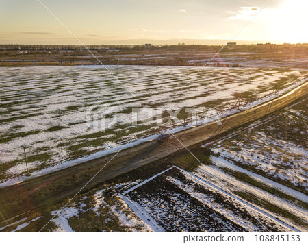 Top view of empty snowy fields patched landscape, dark horizon and bright sky on sunny winter day. Aerial drone photography concept. 108845153