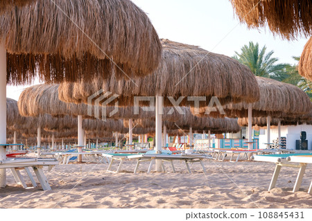 Straw shade umbrella in sea tropical region against blue vibrant sky in summer Straw shade umbrella in sea tropical region against blue vibrant sky in summer 108845431