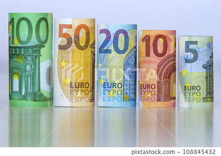 Straight row of accurately rolled hundred, fifty, twenty, ten and five new paper euro banknotes isolated on white background. Symbol of financial prosperity, wealth, success, savings and business. 108845432