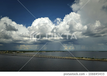 Stormy clouds forming from evaporating humidity of ocean water before thunderstorm over traffic bridge connecting Punta Gorda and Port Charlotte over Peace River. Bad weather conditions for driving 108845433