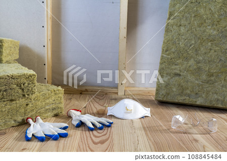 Rock wool and fiberglass insulation staff material for cold barrier. Tools for work with glass wool: protective goggles, glasses and mask. Warm home, economy, construction and renovation concept. 108845484