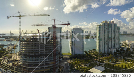New construction site of developing residense in american urban area. Industrial tower lifting cranes in Miami, Florida. Concept of housing growth in the USA New construction site of developing residense in american urban area. Industrial tower lifting cranes in Miami, Florida. Concept of housing growth in the USA 108845820