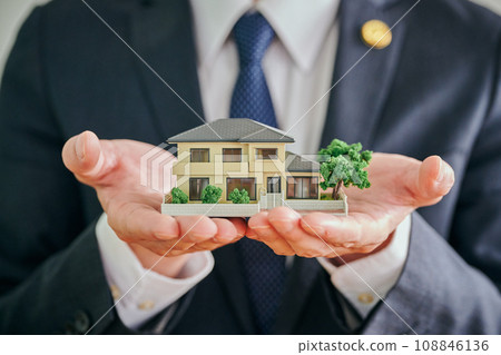 A male lawyer holding a house model in his palm A male lawyer holding a house model in his palm 108846136