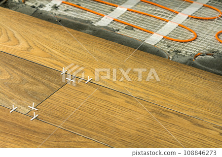 Installation of ceramic tiles and heating elements in warm tile floor. Renovation and improvement concept. 108846273