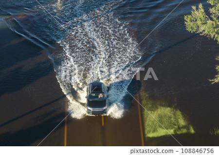 Flooded road in Florida after heavy hurricane rainfall. Aerial view of evacuating cars and surrounded with water houses in suburban residential area 108846756