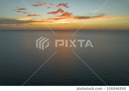 Dramatic bright red sky at ocean sunset, soft evening clouds over sea dark water 108846898