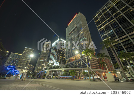 Downtown of Miami Brickell in Florida, USA. Brightly illuminated high skyscraper buildings and street with car trails and metrorail traffic in modern american midtown Downtown of Miami Brickell in Florida, USA. Brightly illuminated high skyscraper buildings and street with car trails and metrorail traffic in modern american midtown 108846902