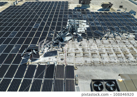 Destroyed by hurricane winds broken down photovoltaic solar panels mounted on industrial building roof for producing green ecological electricity. Consequences of natural disaster in Florida Destroyed by hurricane winds broken down photovoltaic solar panels mounted on industrial building roof for producing green ecological electricity. Consequences of natural disaster in Florida 108846920
