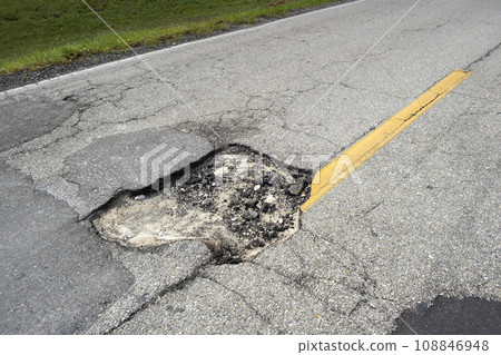 Dangerous pothole on american road surface. Ruined driveway in urgent need of repair 108846948