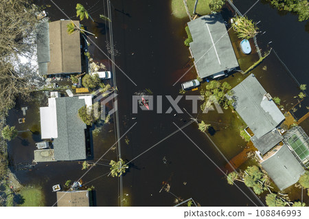 Consequences of natural disaster. Kayak boat floating on flooded street surrounded by hurricane Ian rainfall flood waters homes in Florida residential area 108846993