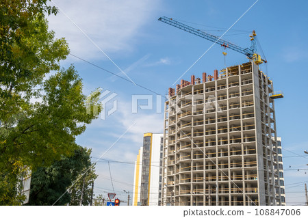 Concrete frame of tall apartment building under construction and tower crane in a city. Concrete frame of tall apartment building under construction and tower crane in a city. 108847006