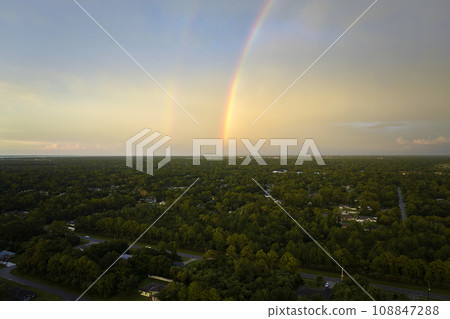Colorful round rainbow over rural town suburbs against blue evening sky after heavy thunderstorm Colorful round rainbow over rural town suburbs against blue evening sky after heavy thunderstorm 108847288