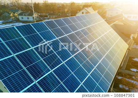 Close-up surface of lit by sun blue shiny solar photo voltaic panels system on building roof. Renewable ecological green energy production concept. Close-up surface of lit by sun blue shiny solar photo voltaic panels system on building roof. Renewable ecological green energy production concept. 108847301