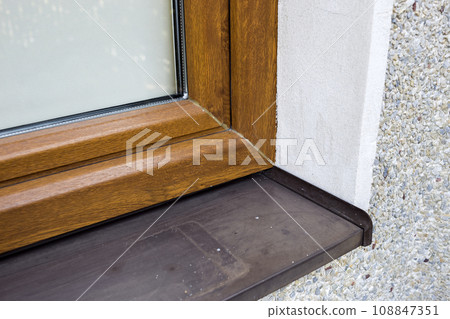 Close-up detail of white plastered house wall with newly installed new brown plastic window and metal windowsill. Modern technology, warm and comfortable home, professional job concept. 108847351
