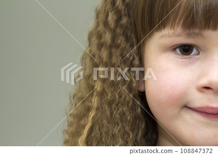 Close up portrait of happy smiling little girl with beautiful thick hair. Part view 108847372