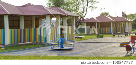 Beautiful new modern playground in kindergarten with soft pavement, bright new multicolored alcoves, swings, slides, benches, roundabout and sandbox. Perfect place for children activities outdoors. 108847757