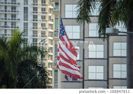 American flag waving in front of Miami skyline. Aerial view of USA stars and stripes spangled banner as symbol of democracy 108847811