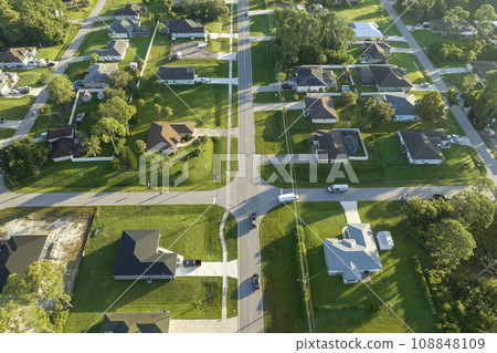 Aerial view of street traffic with driving cars in small town. American suburban landscape with private homes between green palm trees in Florida quiet residential area Aerial view of street traffic with driving cars in small town. American suburban landscape with private homes between green palm trees in Florida quiet residential area 108848109