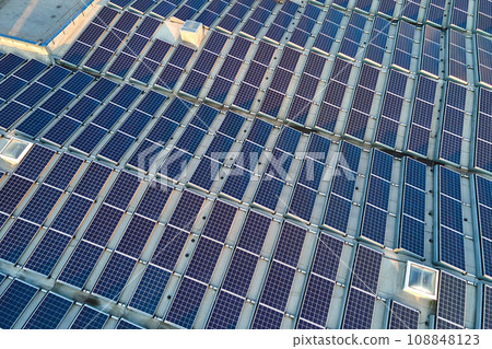 Aerial view of solar power plant with blue photovoltaic panels mounted on industrial building roof for producing green ecological electricity. Production of sustainable energy concept 108848123