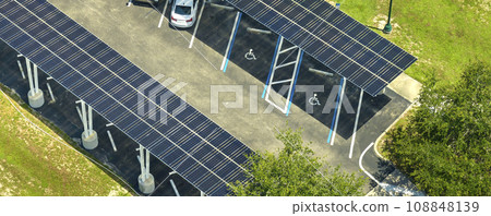 Aerial view of solar panels installed as shade roof over parking lot for parked cars for effective generation of clean electricity. Photovoltaic technology integrated in urban infrastructure Aerial view of solar panels installed as shade roof over parking lot for parked cars for effective generation of clean electricity. Photovoltaic technology integrated in urban infrastructure 108848139