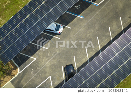 Aerial view of solar panels installed as shade roof over parking lot for parked cars for effective generation of clean electricity. Photovoltaic technology integrated in urban infrastructure Aerial view of solar panels installed as shade roof over parking lot for parked cars for effective generation of clean electricity. Photovoltaic technology integrated in urban infrastructure 108848141
