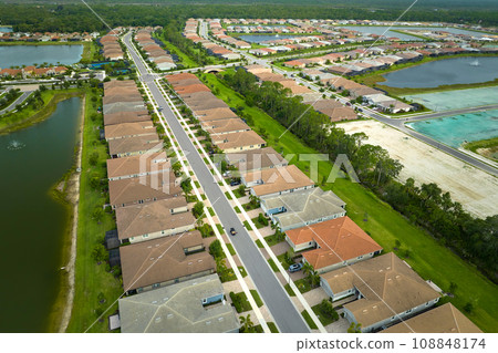 Aerial view of real estate development with tightly located family houses under construction in Florida closed suburban area. Concept of growing american suburbs Aerial view of real estate development with tightly located family houses under construction in Florida closed suburban area. Concept of growing american suburbs 108848174