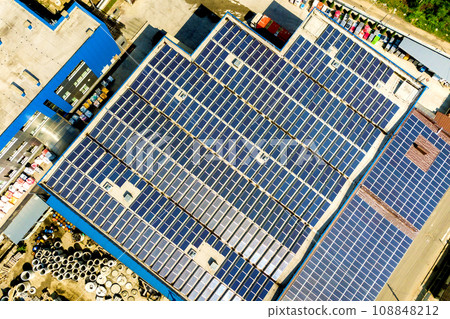 Aerial view of many photo voltaic solar panels mounted of industrial building roof. 108848212