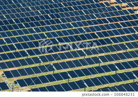 Aerial view of large sustainable electrical power plant with rows of solar photovoltaic panels for producing clean electric energy. Concept of renewable electricity with zero emission Aerial view of large sustainable electrical power plant with rows of solar photovoltaic panels for producing clean electric energy. Concept of renewable electricity with zero emission 108848231