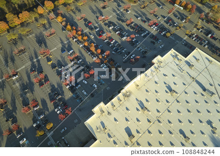 Aerial view of large parking lot in front of rgocery store with many parked colorful cars. Carpark at supercenter shopping mall with lines and markings for vehicle places and directions Aerial view of large parking lot in front of rgocery store with many parked colorful cars. Carpark at supercenter shopping mall with lines and markings for vehicle places and directions 108848244