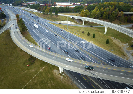 Aerial view of american freeway intersection with fast moving cars and trucks. USA transportation infrastructure concept Aerial view of american freeway intersection with fast moving cars and trucks. USA transportation infrastructure concept 108848727
