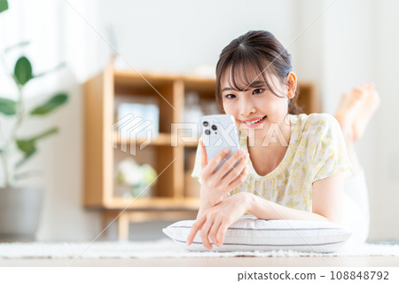 A woman who operates a smartphone in the living room. A woman who operates a smartphone in the living room. 108848792