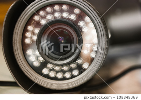 Close-up front view of a surveillance camera lens. An electronic tool. Video recorder. CCTV cameras, surveillance, monitoring, control and protection, guard of private territory, home, office. 108849369