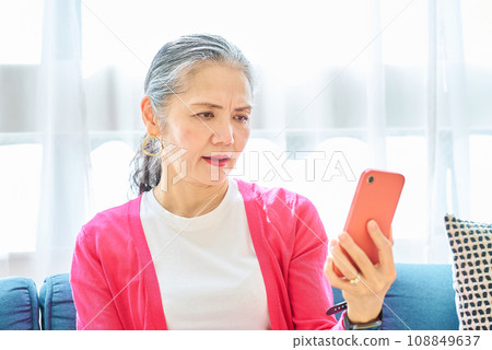 A senior woman looking at her smartphone screen with a troubled expression A senior woman looking at her smartphone screen with a troubled expression 108849637