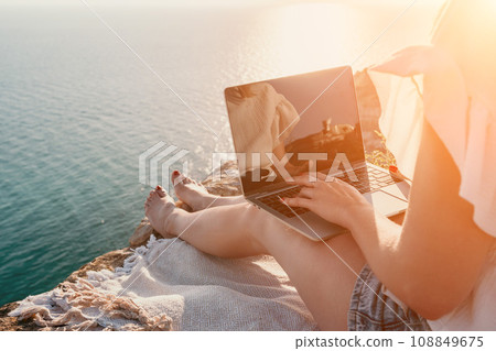 Woman sea laptop. Business woman working on laptop by sea at sunset. Close up on hands of pretty lady typing on computer outdoors summer day. Freelance, digital nomad, travel and holidays concept. Woman sea laptop. Business woman working on laptop by sea at sunset. Close up on hands of pretty lady typing on computer outdoors summer day. Freelance, digital nomad, travel and holidays concept. 108849675