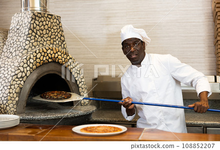 Emotional man chef preparing pizza in pizzeria 108852207