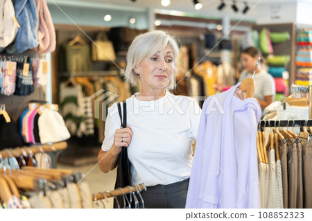 Woman flips through racks of hoodies 108852323