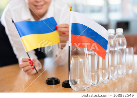 Unrecognizable girl sets midget flags of Russia and Ukraine before international negotiations 108852549