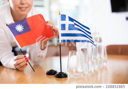 Employee of delegation prepares negotiating table - sets up flag of Greece and Taiwan 108852865